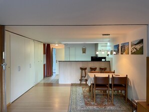A modern kitchen with a central island, wooden dining table with chairs, and a patterned rug. - Domino 15 # 2-bed apartment, Dusche, WC 2-bed apartment, Dusche, WC by Interhome (Leukerbad)