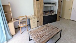 Una habitación con cama, escritorio, silla y armario.