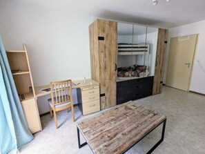 Ein Zimmer mit einem Bett, einem Schreibtisch, einem Stuhl und einem Kleiderschrank.