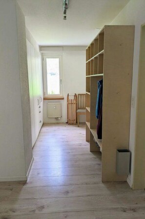 A hallway with a wooden floor, a radiator, a window, and a built-in wardrobe with shelves. - Petit Trianon 103 # 8-bed apartment, Bad, WC 8-bed apartment, Bad, WC by Interhome (Leukerbad)