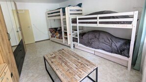 Una habitación tipo dormitorio con literas, un banco de madera y un armario.