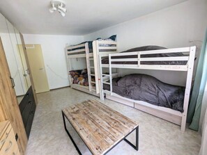 Ein Schlafsaalzimmer mit Etagenbetten, einer Holzbänkl und einem Kleiderschrank.
