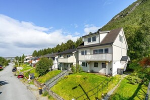 Eine Wohnstraße mit Häusern, wolkenlosem Himmel und hügeliger Landschaft.