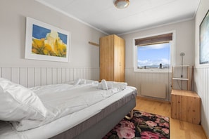 Ein Schlafzimmer mit einem Bett, einem Holzschrank, einem Fenster mit Blick und einem Bild an der Wand.