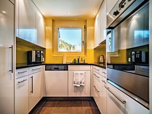 A modern kitchen with stainless steel appliances, a window with a mountain view, and a tiled floor. - Brüggli A14 Appartement/Fewo, Bad, WC, 4-Bettwohnung by Interhome (Arosa)