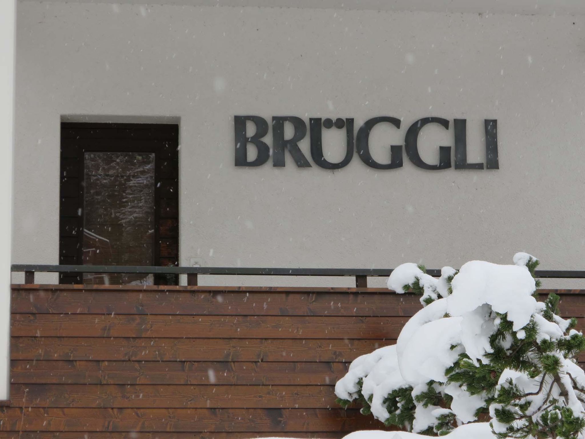 A building with a sign that reads 'BRUGGLI' and a wooden fence in front.