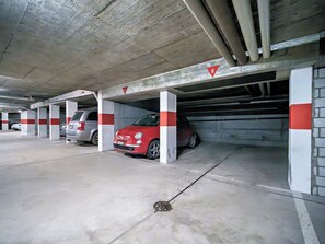 A parking garage with concrete pillars, marked parking spaces, and a red car parked in one of the spaces. - Brüggli A14 Appartement/Fewo, Bad, WC, 4-Bettwohnung by Interhome (Arosa)