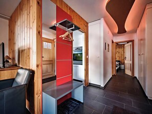 A modern kitchen with a red accent wall, wooden paneling, and a stainless steel range hood. - Brüggli A14 Appartement/Fewo, Bad, WC, 4-Bettwohnung by Interhome (Arosa)