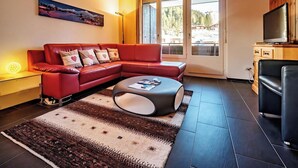 Ein modernes Wohnzimmer mit einem roten Sofa, einem Couchtisch und einem Fernseher auf einer Holzkommode.