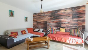 Een moderne woonkamer met een bank, een salontafel en een bed met metalen frame.