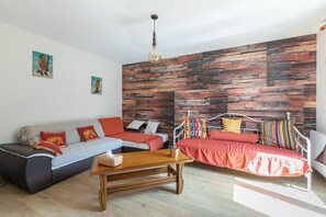 A modern living room with a sofa, a coffee table, and a bed with a metal frame. - L'Oustaou des Adrets - Proche station de ski (Le Lauzet-Ubaye)
