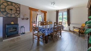 Een eetruimte met een houten tafel, stoelen, een grote wandklok en een open haard.