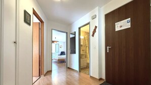 Un corridoio d'hotel con pavimento in legno, un tappetino e una porta con il segnale di parcheggio.