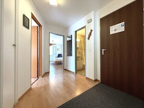 A hotel hallway with wooden flooring, a doormat, and a door with a parking sign. - Royal 32 # 6-bed apartment, Dusche, WC 6-Bettwohnung, Dusche, WC by Interhome (Leukerbad)