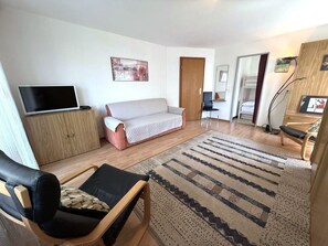 Een moderne woonkamer met een bank, een televisie, een houten kast en een kamerkleed met een patroon.