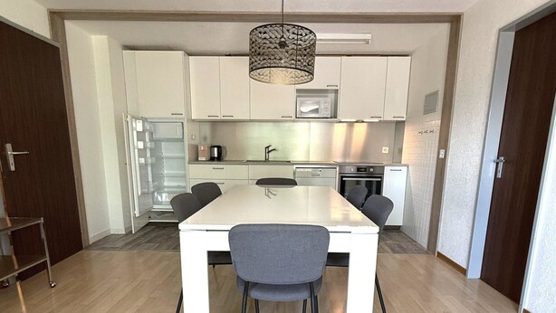 Una cucina moderna con mobili bianchi, un piano di lavoro in acciaio inossidabile e un forno integrato.