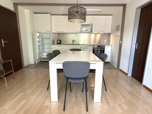 Een moderne keuken met witte kastjes, een roestvrijstalen aanrecht en een ingebouwde oven.