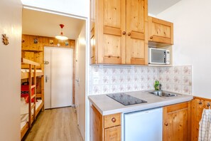 A kitchen with wooden cabinets, a microwave, a Bosch dishwasher, and a tiled backsplash. - Studio Samoëns - Station de ski accessible à pied (Samoëns)