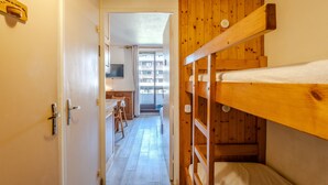 Un pasillo estrecho con una cama litera de madera, una kitchenette y vistas a un balcón.