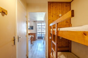 A narrow hallway with a wooden bunk bed, a kitchenette, and a view of a balcony. - Studio Samoëns - Station de ski accessible à pied (Samoëns)