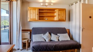 Un dormitorio con cama, cabecero de madera, mesita de noche y una ventana con cortinas.