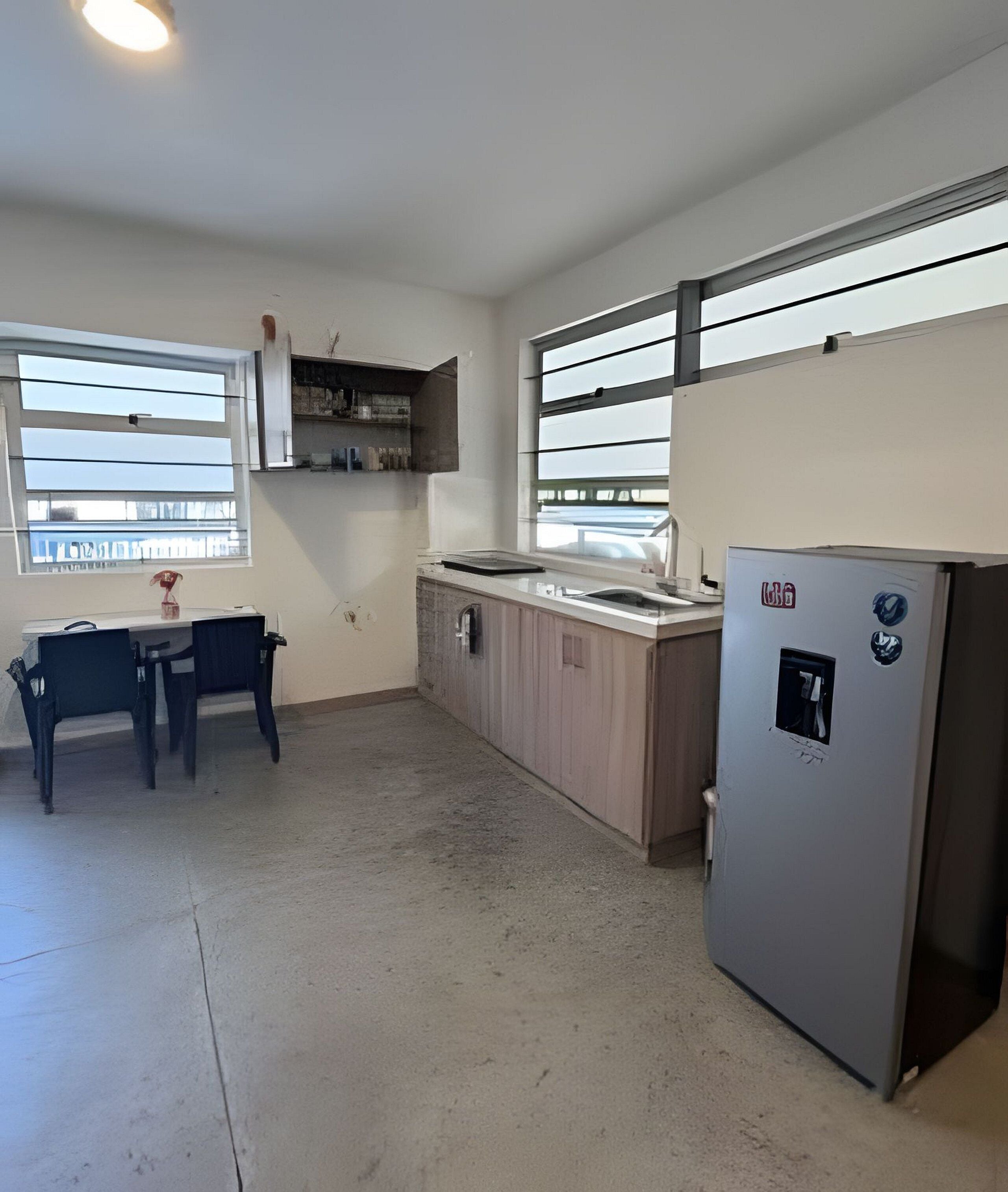 Una cocina con refrigerador, pileta y ventana.