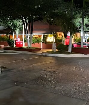 A street view at night with a building featuring a red awning and a signboard.