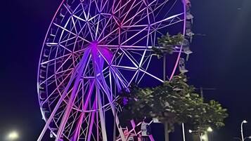 A large Ferris wheel with a geometric design, surrounded by people and trees.