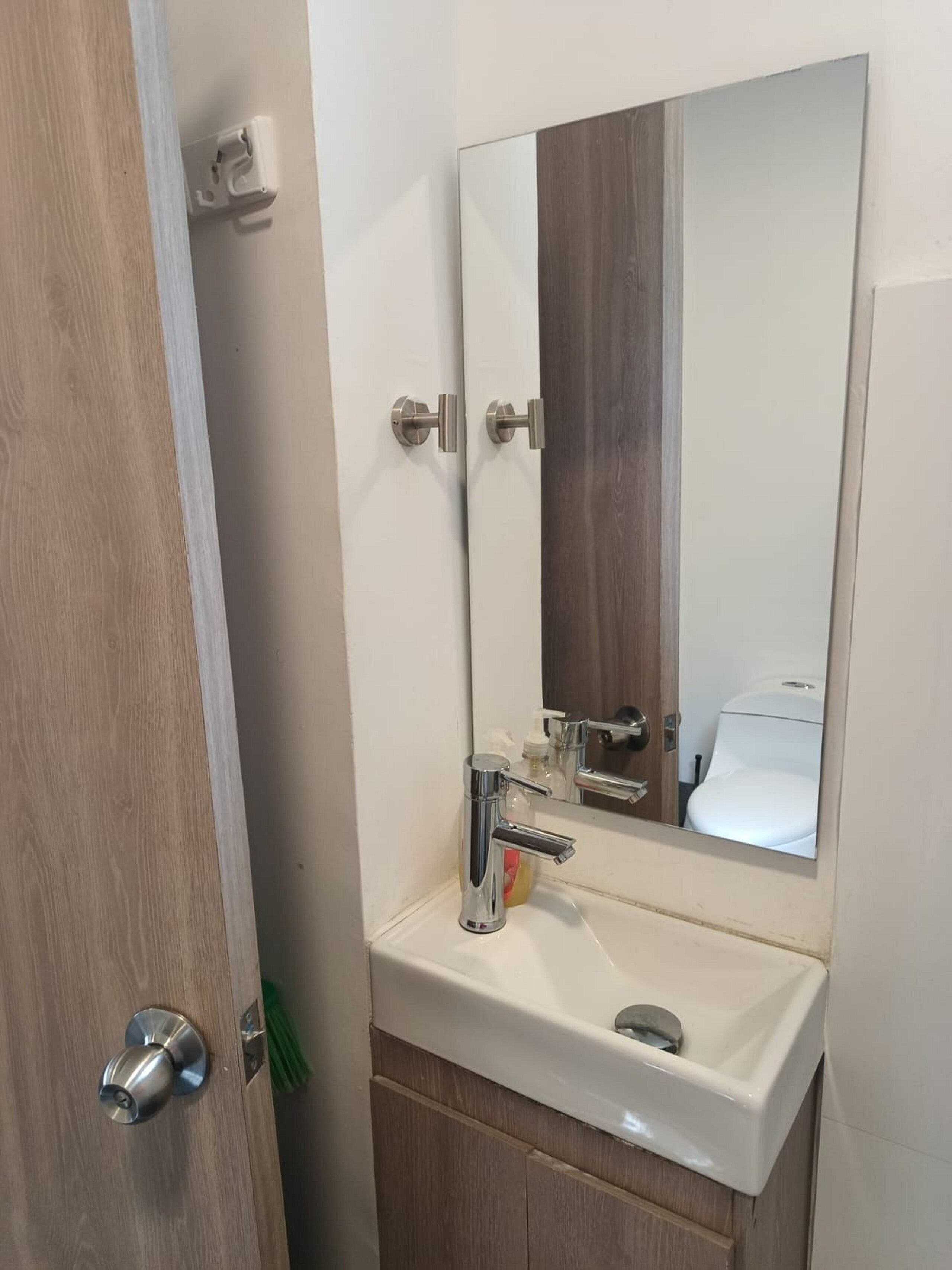 Un baño con un lavabo blanco, un espejo y una puerta de madera.