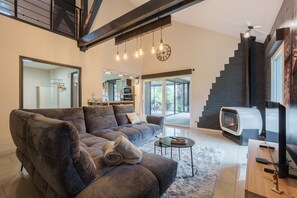 Una sala de estar moderna con un sofá grande, una chimenea, un televisor y una escalera.