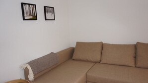 A brown sofa with cushions, a small round table with a round object on it, and two framed pictures on the wall. - Paradies 017 Appartement/Fewo,   4-Bettwohnung by Interhome (Arosa)