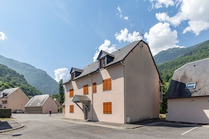 Ein Gebäude mit einem geneigten Dach, mehreren Fenstern und einer sichtbaren Antenne.