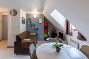 Ein gemütlicher, kleiner Wohnbereich mit einer Couch, einem Esstisch und einem Fernseher.