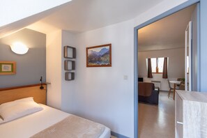 Ein Hotelzimmer mit Bett, Schreibtisch, Stuhl, einem Gemälde und Blick auf den Speisesaal.