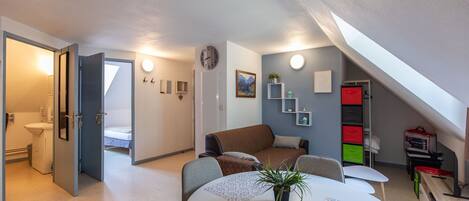 Ein modernes Wohnzimmer mit rundem Tisch, einer Couch, einer Uhr und einer Treppe, die in ein Obergeschoss führt.