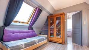 A bedroom with a bed, a window with curtains, a wooden cabinet, and a door leading to another room. - Chez Cathy - Cocon pour 2 à 15 min de la plage (Etaples-sur-Mer)