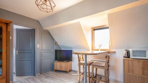 A modern kitchen with a dining area, a television, and a microwave. - Chez Cathy - Cocon pour 2 à 15 min de la plage (Etaples-sur-Mer)