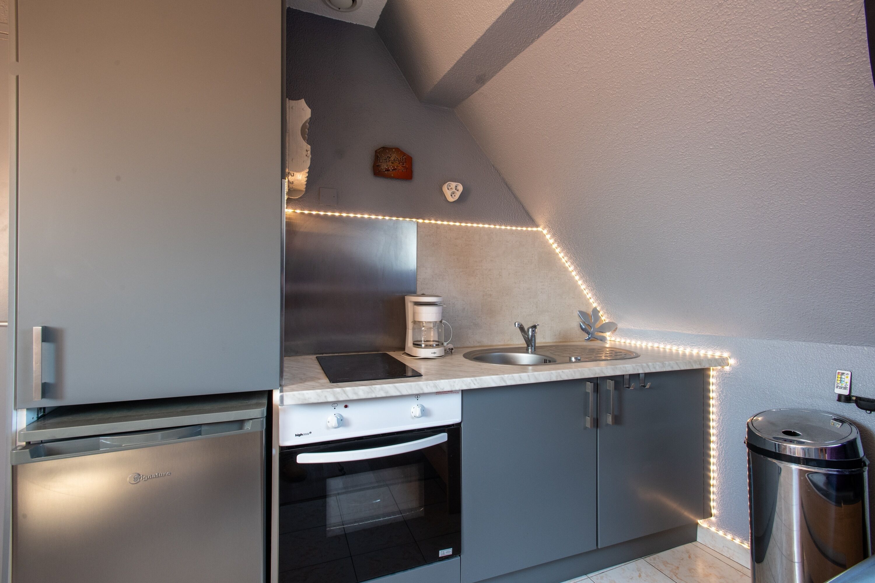 A kitchen with a built-in oven, a coffee maker, and a trash can.