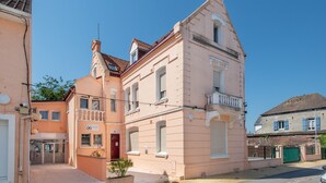 A pink building with a balcony, a red door, and a small garden area. - Chez Cathy - Cocon pour 2 à 15 min de la plage (Etaples-sur-Mer)