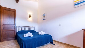 A room with a bed, a wooden door, a wall-mounted light, and a small painting. - Maison Agosta Plage - Pour 5 à 500 m de la plage (Albitreccia)
