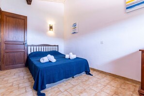 A room with a bed, a wooden door, a wall-mounted light, and a small painting. - Maison Agosta Plage - Pour 5 à 500 m de la plage (Albitreccia)