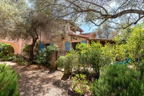 A rustic building with a garden path, a wooden gate, and a hammock. - Maison Agosta Plage - Pour 5 à 500 m de la plage (Albitreccia)