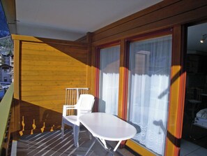 Ein Balkon mit weißem Stuhl und Tisch, Holzwänden und Blick ins Freie.
