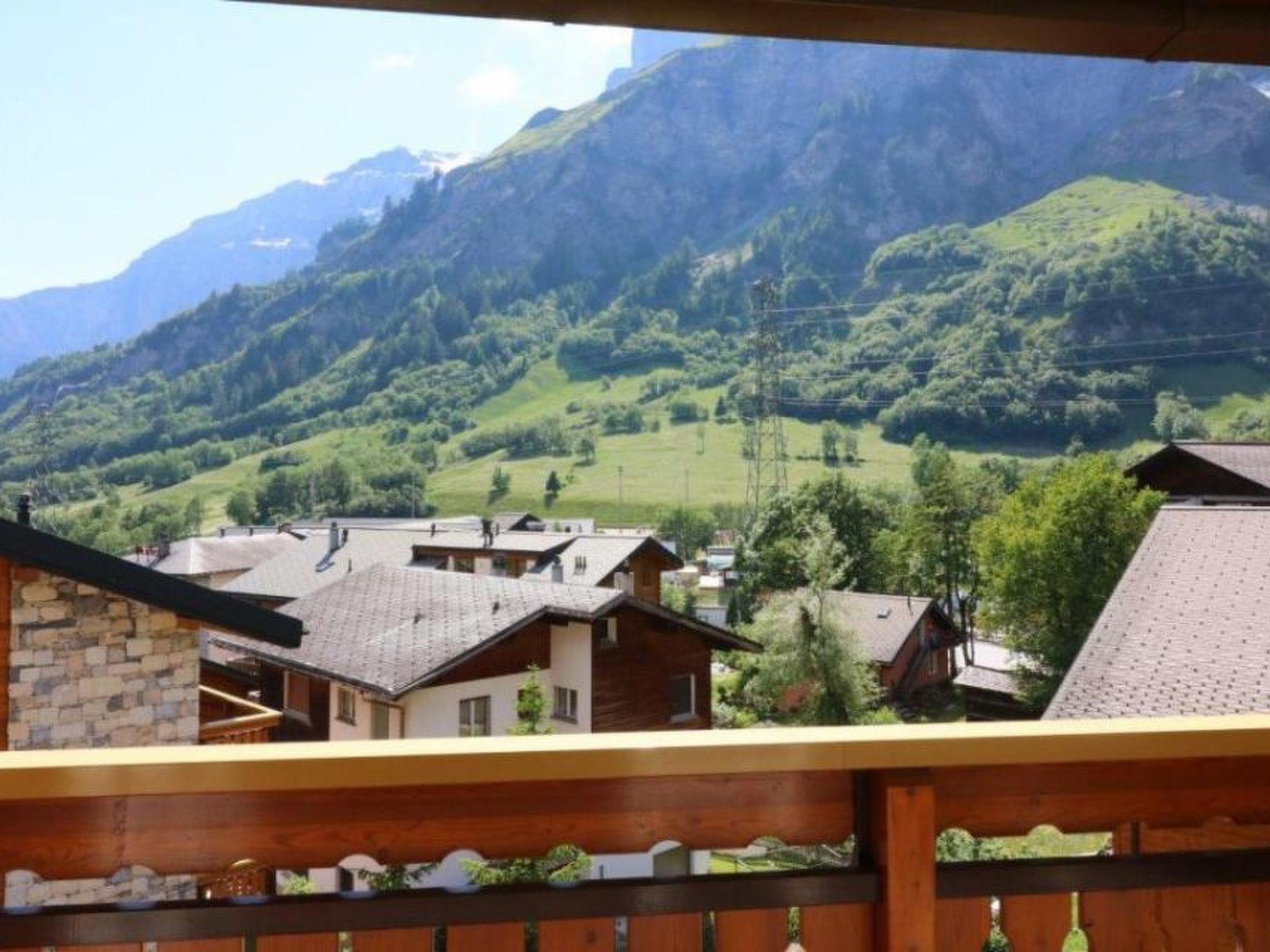 Eine Berglandschaft mit Häusern im Vordergrund und einem Geländer aus Holz.
