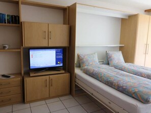 A compact room with a bed, a desk with a computer, and a bookshelf. - Adlerhorst Leukerbad # 2-bed apartment, Dusche, WC by Interhome (Leukerbad)