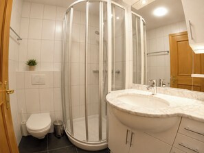 Ein modernes Badezimmer mit einer in Glas eingefassten Dusche, einer weißen Toilette und einem мраморной Waschbecken.