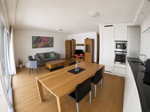 Eine moderne Küche mit weißen Schränken, einem Holzespeisetisch mit schwarzen Stühlen und einem eingebauten Backofen.