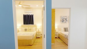 Una camera d'albergo con un letto, comodini, una ventola a soffitto e un condizionatore d'aria a parete.