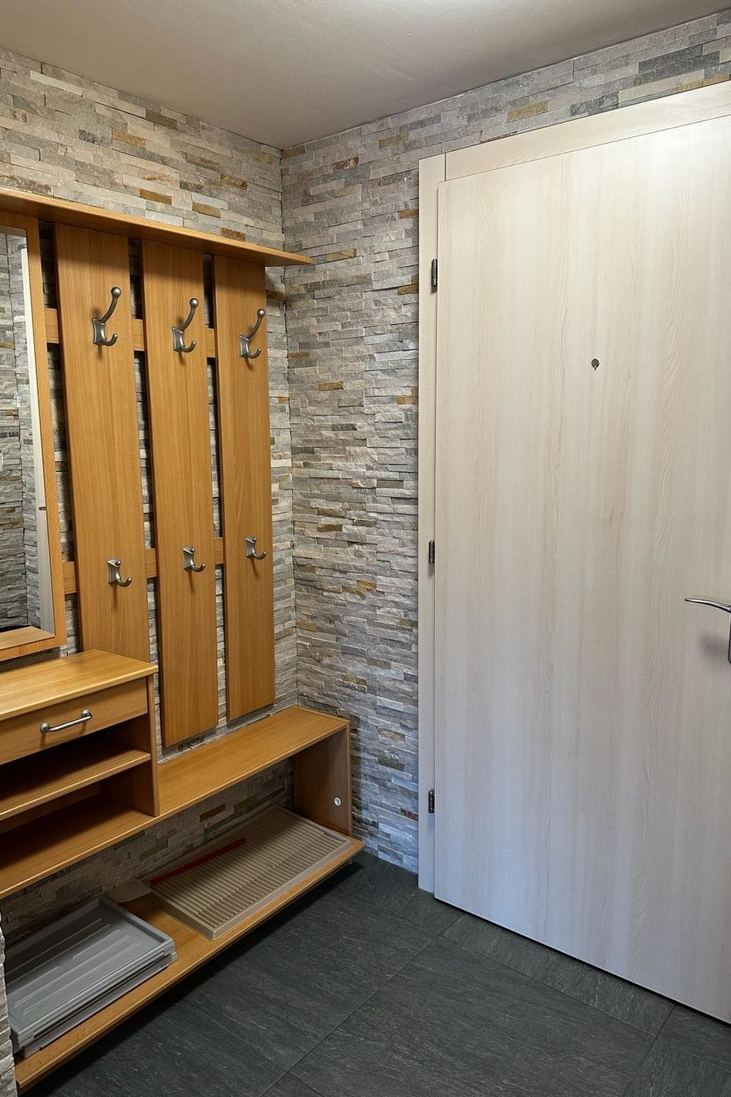 Ein Zimmer mit einer Steinwand, einem Holfischschrank mit mehreren Türen und einer schlichten Tür.