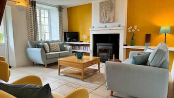 A living room with a sofa, armchairs, a coffee table, a fireplace, and a television.